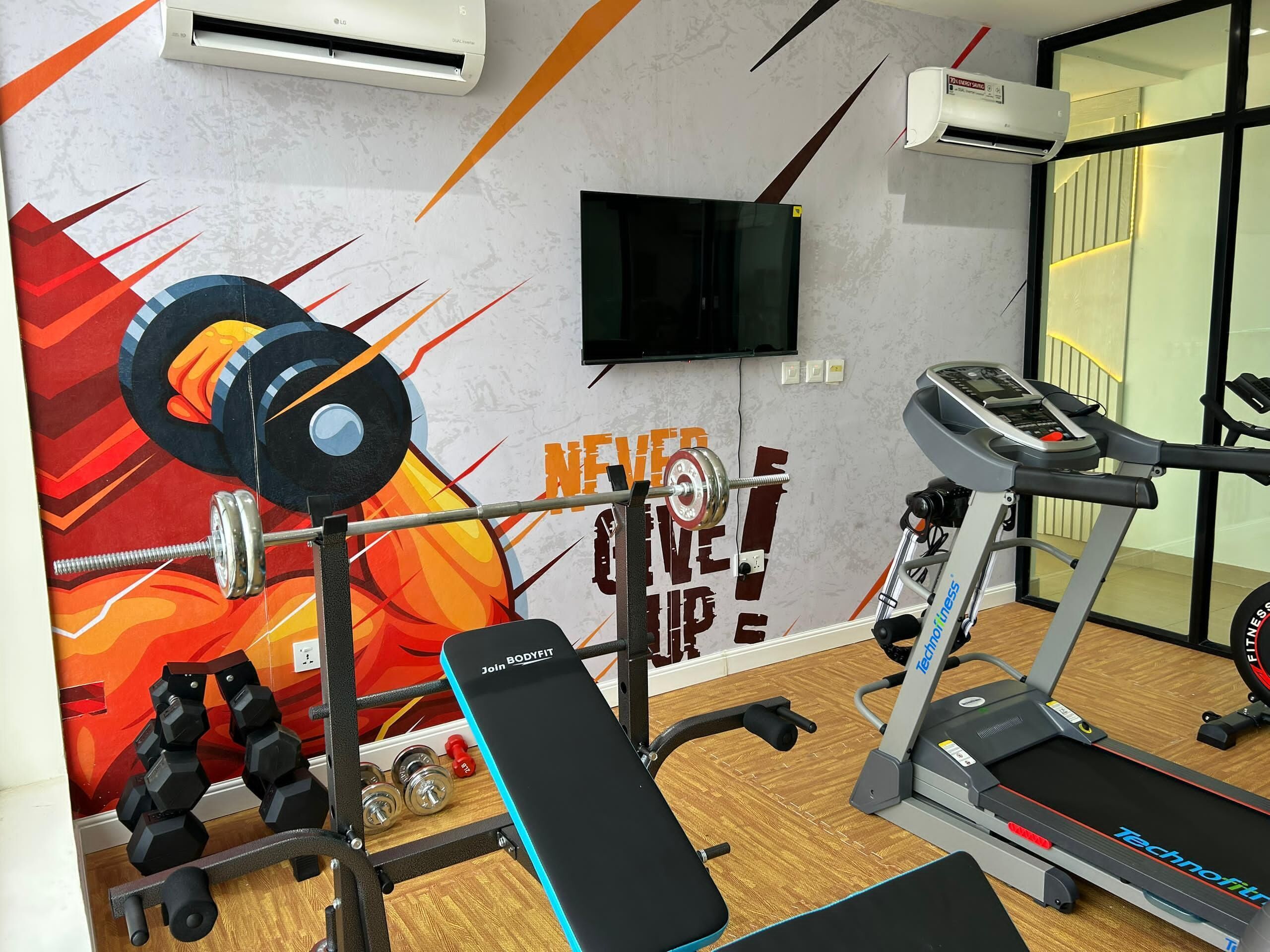 A gym with a wall mural, weightlifting equipment, a treadmill, and a bench.