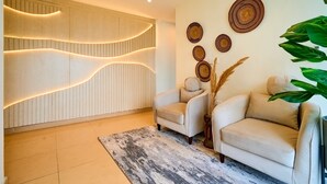 A modern living room with a sofa, a decorative wall, and a large plant.
