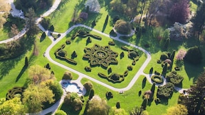 An aerial view of a well-maintained garden with geometric landscaping, pathways, and a central circular design.
