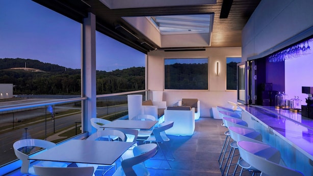 A modern outdoor bar area with seating and a pool, overlooking a road and hills. - Element by Marriott Cartersville (Cartersville)