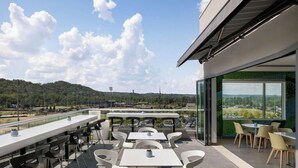 An outdoor terrace with tables and chairs, overlooking a sports field and a parking lot. - Element by Marriott Cartersville (Cartersville)