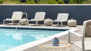 A poolside area with four lounge chairs and two round tables, one with a plant. - Element by Marriott Cartersville (Cartersville)