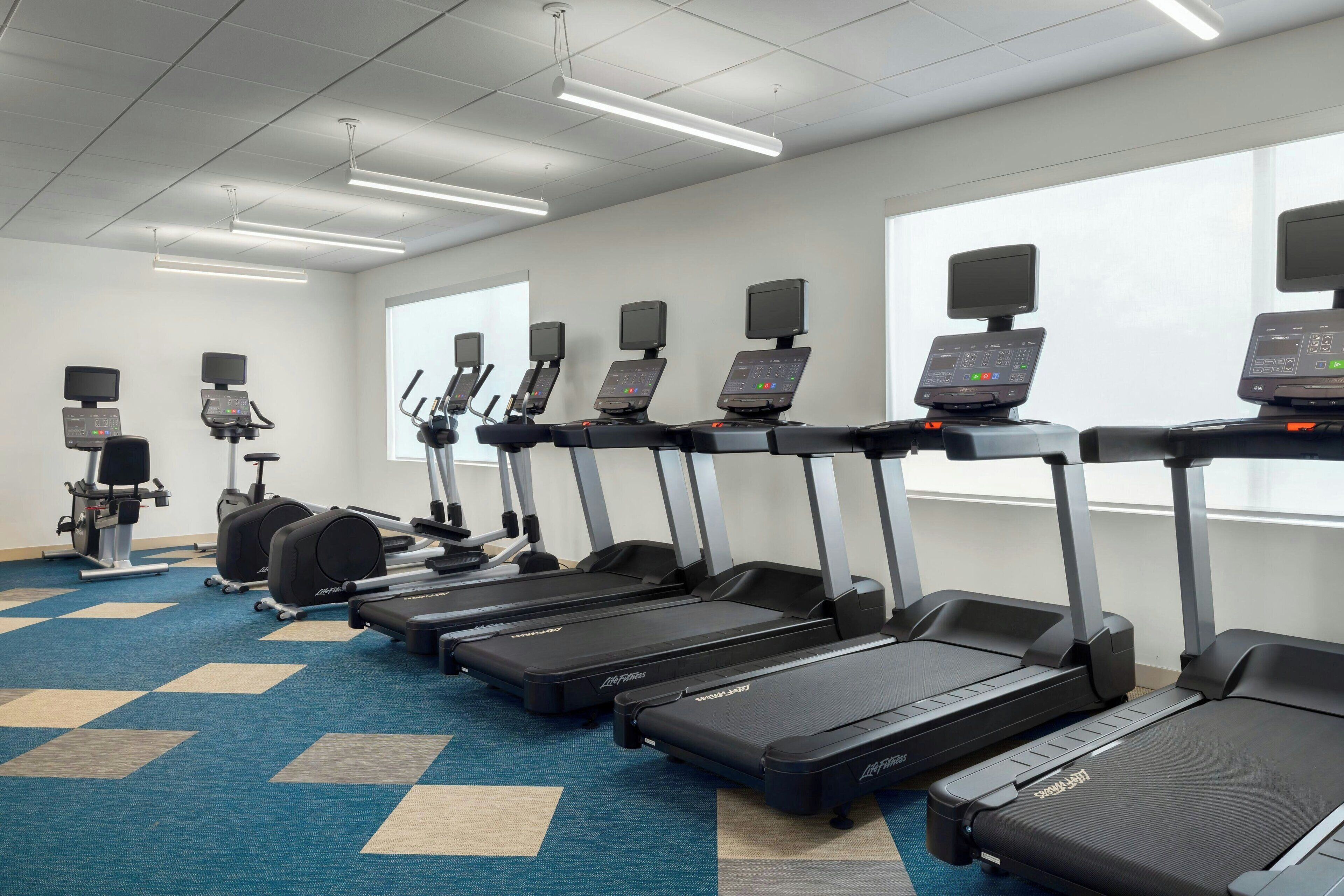 A gym with treadmills, elliptical machines, and stationary bikes.