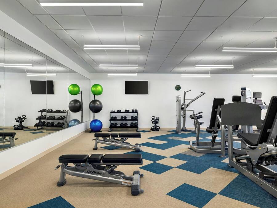 A gym with exercise equipment, mirrors, and a checkered floor.