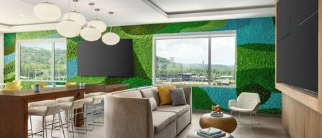 Una sala de estar moderna con un sofá, taburetes de bar, una mesa de centro y un televisor montado en la pared.