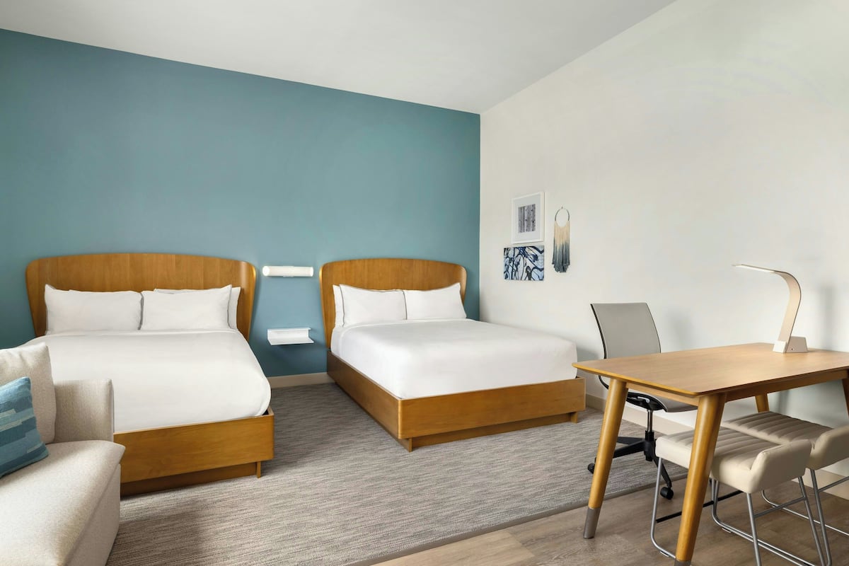 Ett hotellrum med två sängar, ett skrivbord och en stol.
