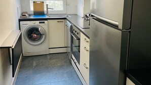 Une cuisine compacte équipée d’un lave-linge, d’un four et d’un grand réfrigérateur.