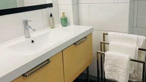 Une salle de bain moderne avec un lavabo blanc, un miroir et un porte-serviettes.