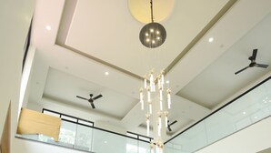 A spacious, multi-level interior with a modern design, featuring a reception desk, seating area, and a chandelier. - Creek Wood (Ramnagar)