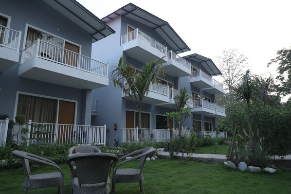A multi-story hotel with balconies, outdoor seating, and a well-maintained garden.
