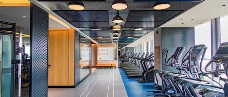 A gym with treadmills and exercise equipment, a wooden bench, and a motivational quote on the wall.