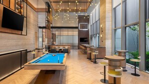 A modern pool table in a well-lit room with large windows, bar area, and seating. - Four Points By Sheraton Yantai (Yantai)