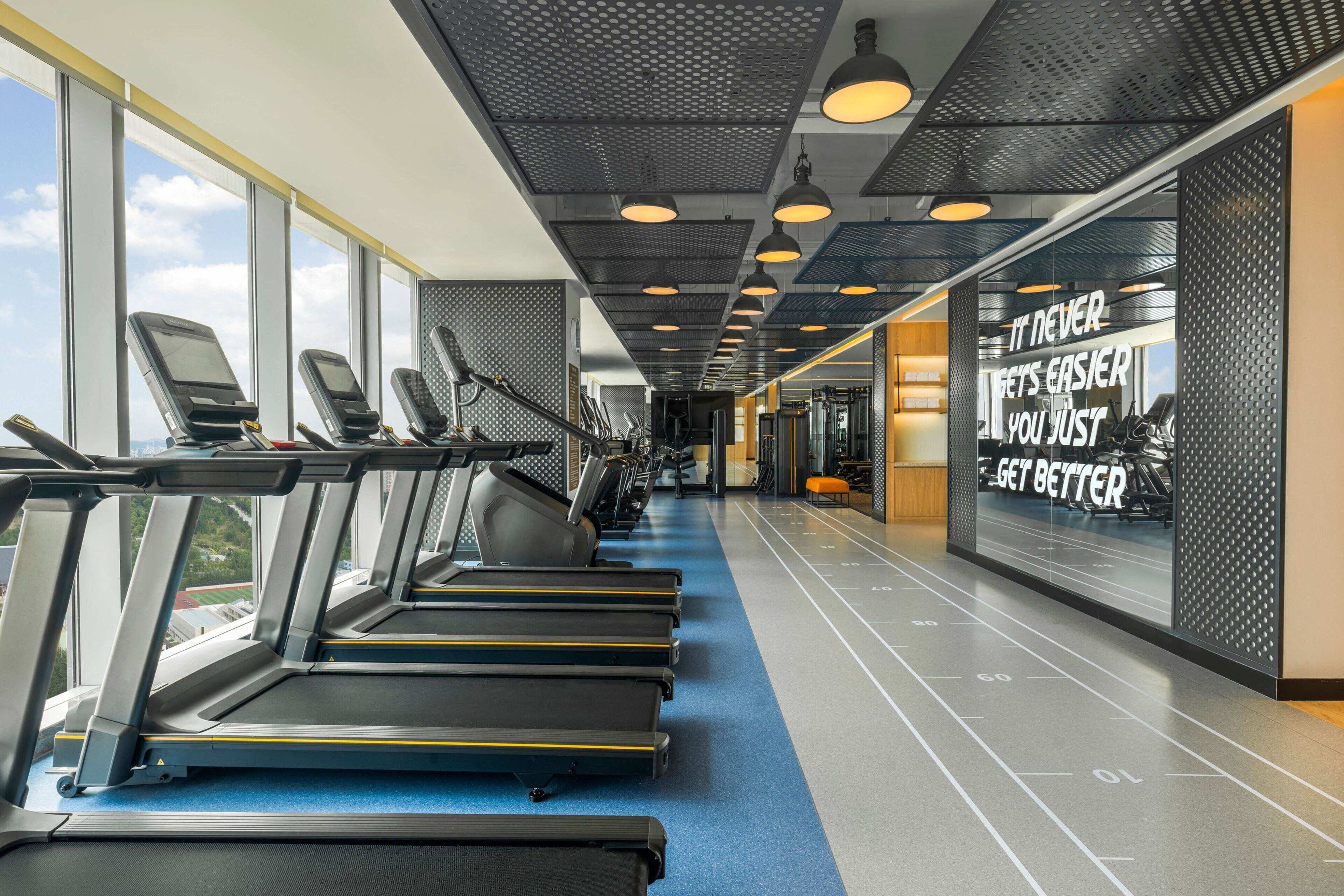 Una palestra con tapis roulant, attrezzi per esercizi e decorazioni motivazionali alle pareti.