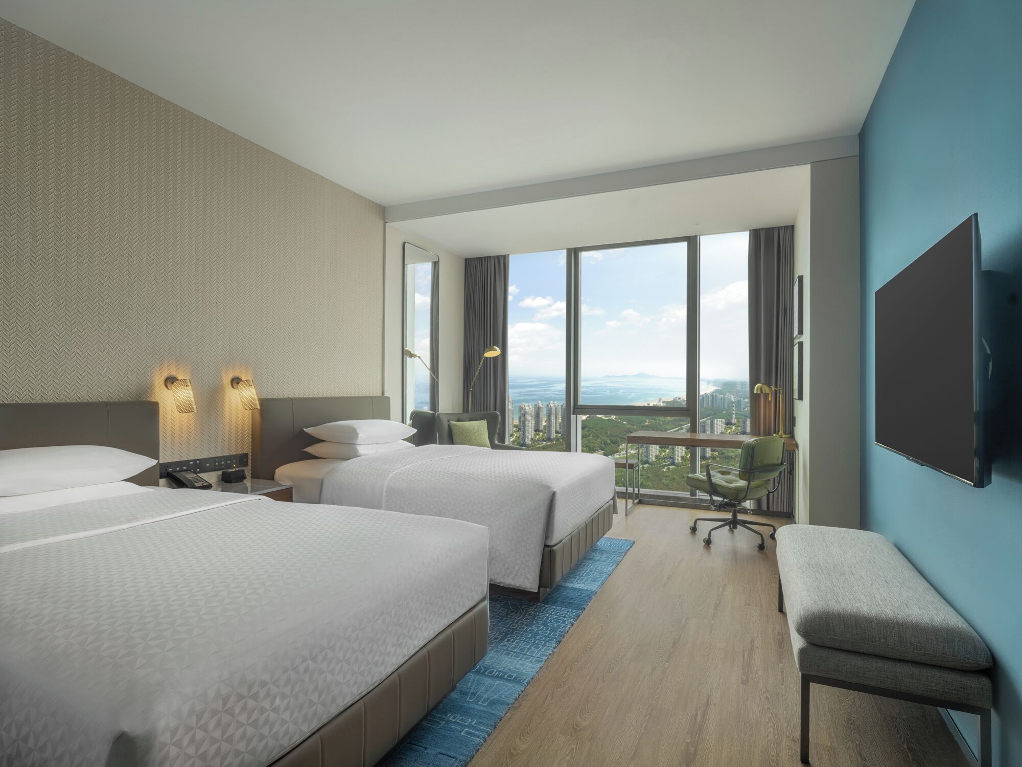 Une chambre d’hôtel moderne équipée de deux lits, d’un bureau, d’une chaise et d’une grande fenêtre donnant sur la ville.