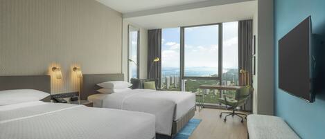 Une chambre d’hôtel moderne équipée de deux lits, d’un bureau, d’une chaise et d’une grande fenêtre donnant sur la ville.