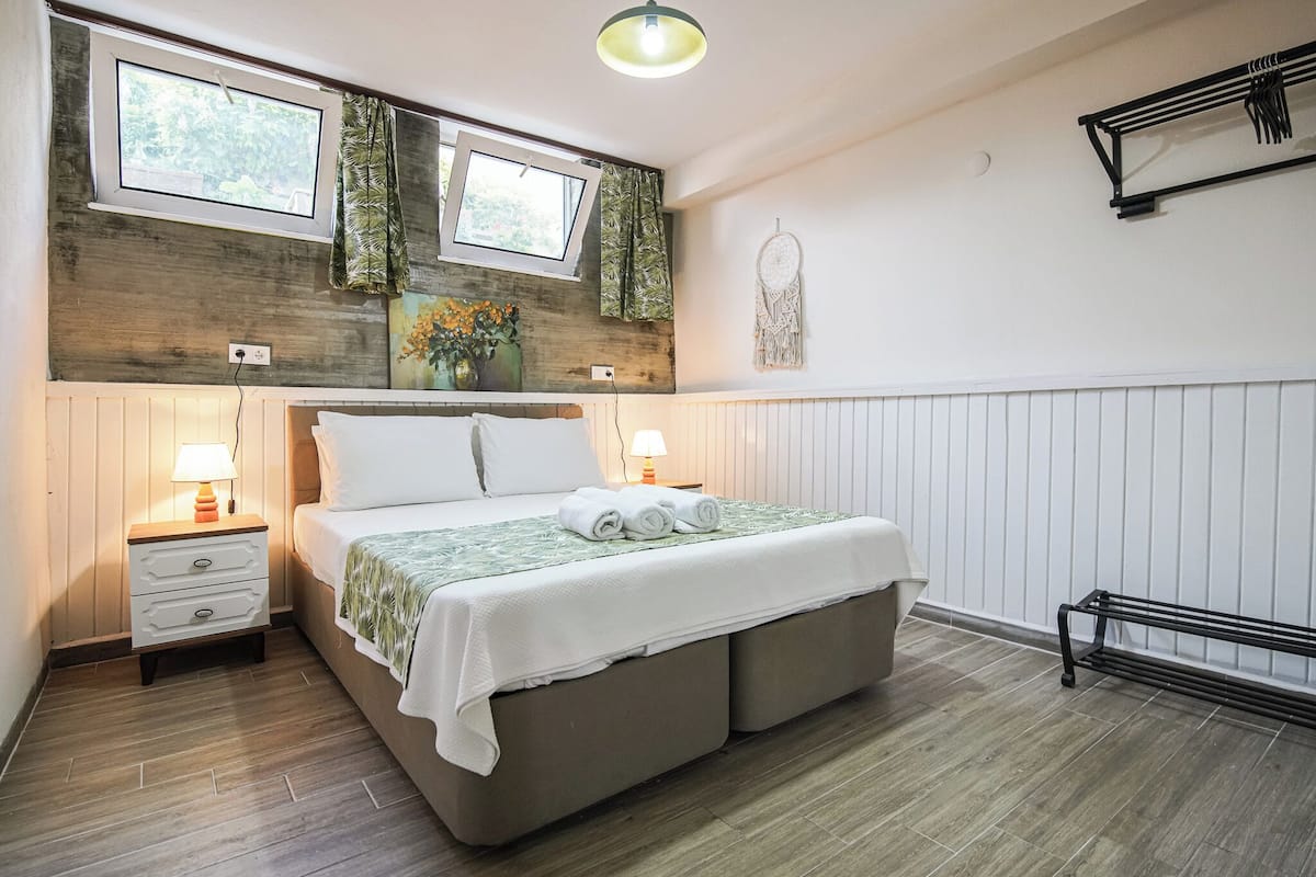 A bedroom with a bed, nightstands, a window, a dreamcatcher, and a bench.