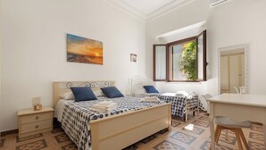 Une chambre à coucher comprenant un lit, des tables de chevet, un bureau et une fenêtre donnant sur un paysage verdoyant.