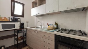 Une cuisine moderne équipée d’un four à micro-ondes, d’un évier, d’une cuisinière à gaz et de meubles de rangement en bois.