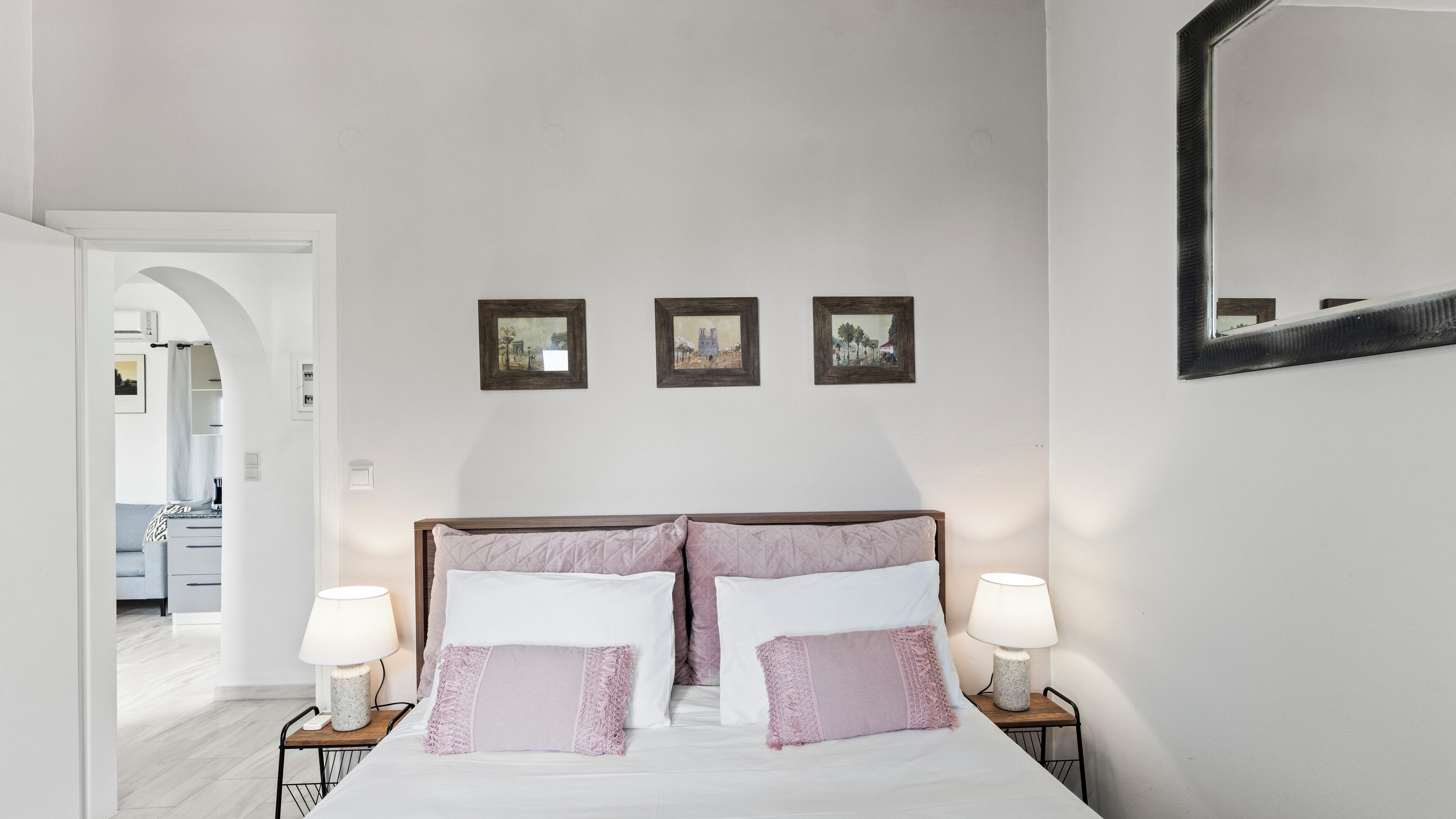 Ein Schlafzimmer mit einem Bett, zwei Nachttischen und drei gerahmten Bildern an der Wand.