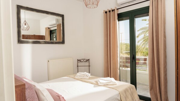Un dormitorio con cama, radiador, espejo y vistas al exterior a través de una puerta corrediza.