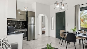 Una cocina moderna con horno integrado, refrigerador de acero inoxidable y comedor con mesa y sillas.