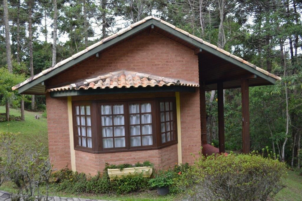 A small brick building with a pitched roof and a window with multiple panes.