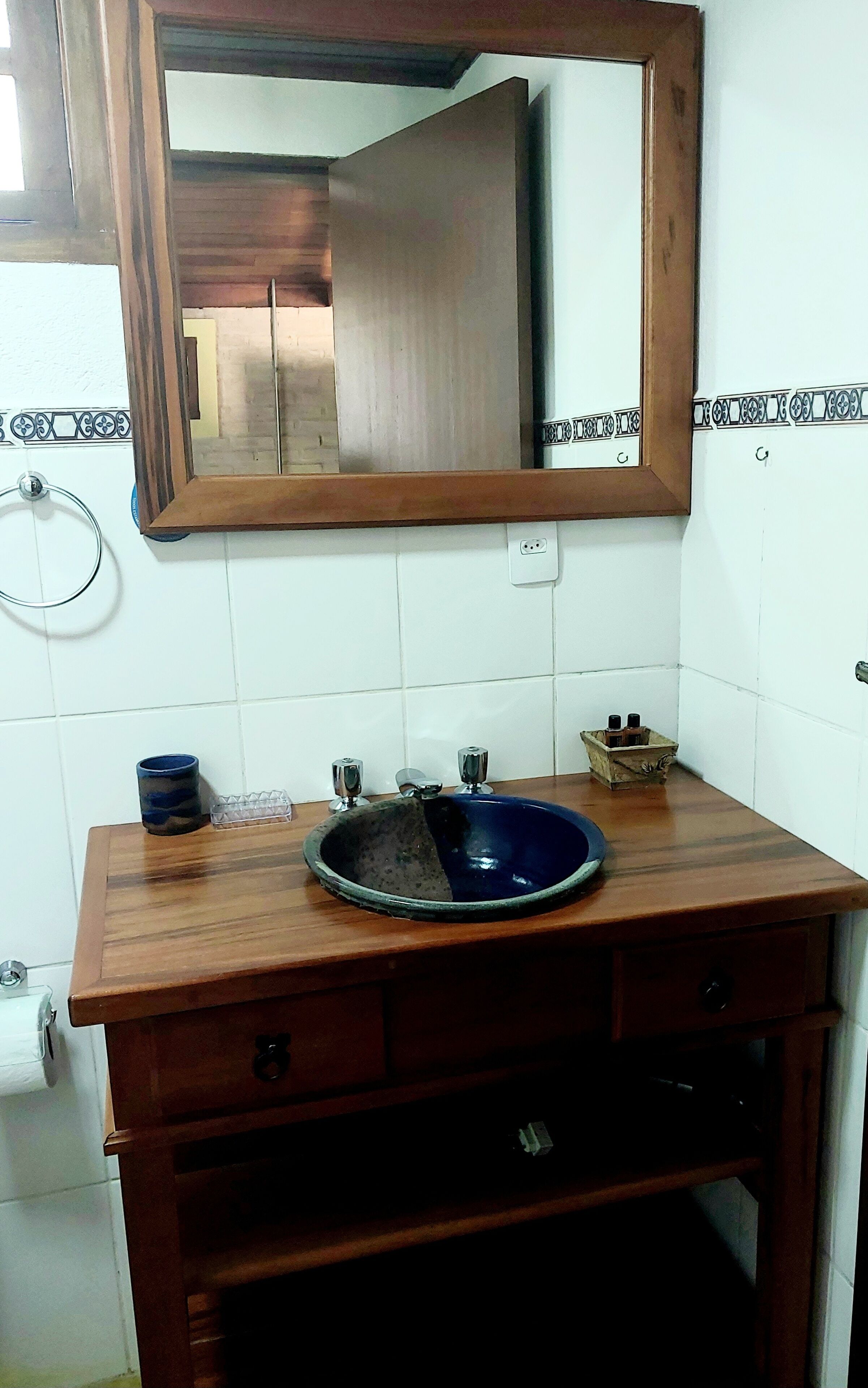 A bathroom with a wooden vanity, a blue sink, and a mirror.