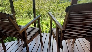 A wooden deck with two chairs facing a lush green landscape. - Pousada Candeias Ltda (Cunha)