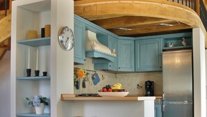 Eine Küche mit blauen Schränken, einem Edelstahlkühlschrank und einer Holztreppe.
