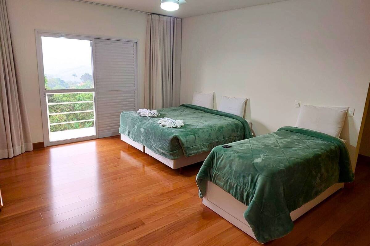 Une chambre avec deux lits, un ventilateur de plafond et une grande fenêtre avec des rideaux.