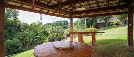 A covered outdoor area with a large, round wooden table and a bench.