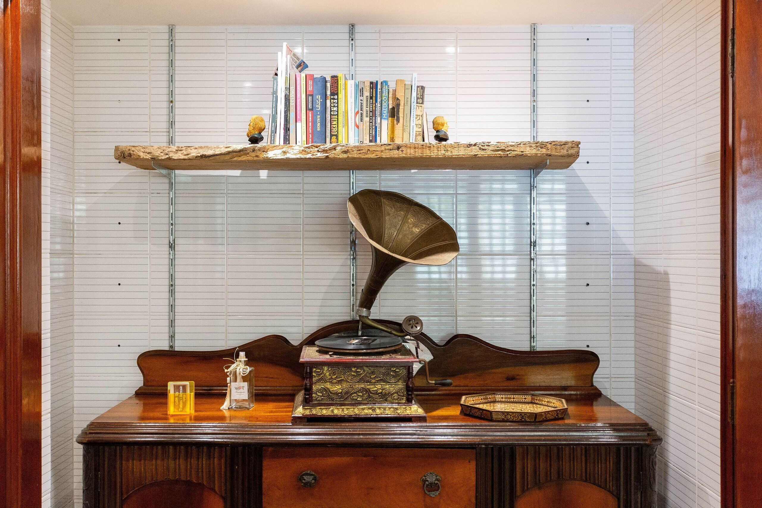 A vintage desk with a gramophone, books on a shelf, and a decorative lamp.