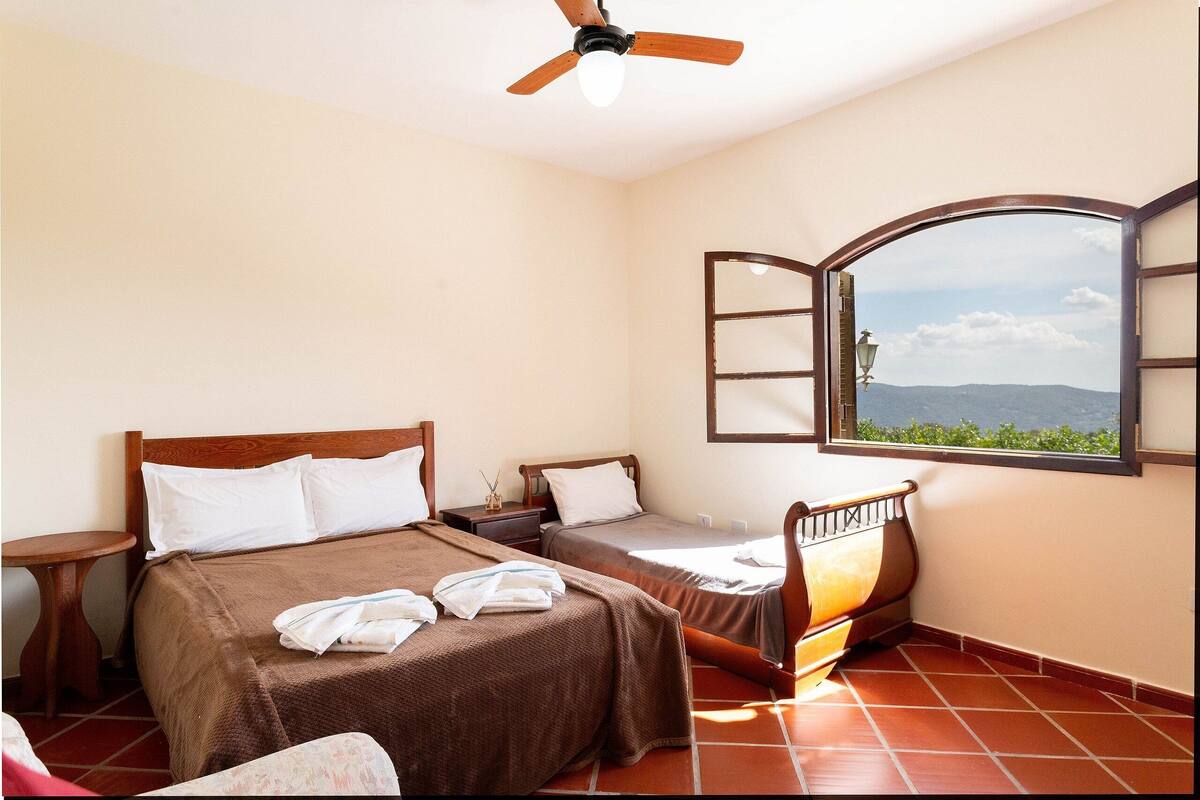 Une chambre avec deux lits, un ventilateur de plafond, une fenêtre avec vue et une table de chevet.