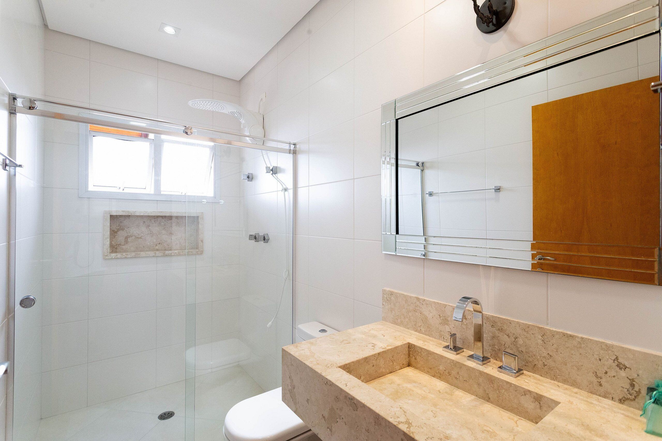 A modern bathroom with a glass shower enclosure, a marble sink, and a large mirror.