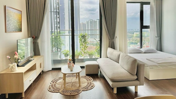 A modern hotel room with a sofa, a bed, a TV, and a balcony with a city view.
