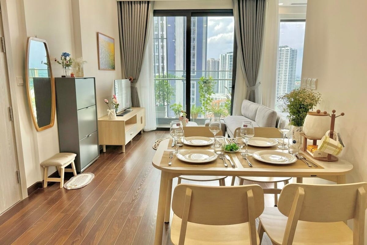 A dining area with a table set for four, a sofa, and a view of the city through large windows.
