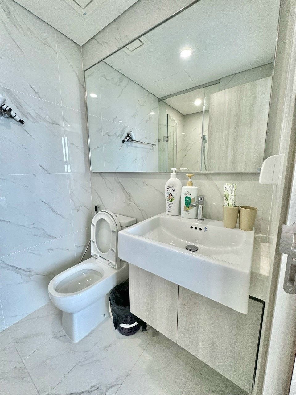 Un baño moderno con inodoro, lavamanos y espejo.