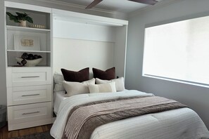 Une chambre avec un lit, une armoire intégrée, une fenêtre et une plante.