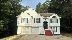 A two-story house with a front entrance, a driveway, and a small front yard. - Charming Locust Grove GetAwayHome 4bd/3bath (Locust Grove)