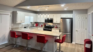 A modern kitchen with white cabinets, a stainless steel refrigerator, a built-in oven, and a granite countertop. - Charming Locust Grove GetAwayHome 4bd/3bath (Locust Grove)