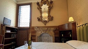 Ein Hotelzimmer mit einem Bett, einer Holzbibliothek, einem Kamin und einem großen Spiegel an der Wand.