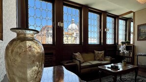 Ein Zimmer mit großen Fenstern, einem Sofa, einem Tisch und einer Vase.