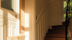 Una escalera de madera con barandilla de metal que conduce a una puerta con un ventanal encima.