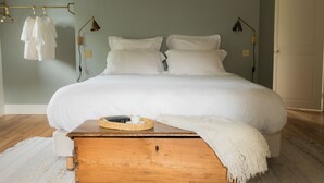 Un dormitorio con una cama grande, una mesita de noche de madera, una lámpara y un perchero.