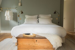 Un dormitorio con una cama grande, una mesita de noche de madera, una lámpara y un perchero.