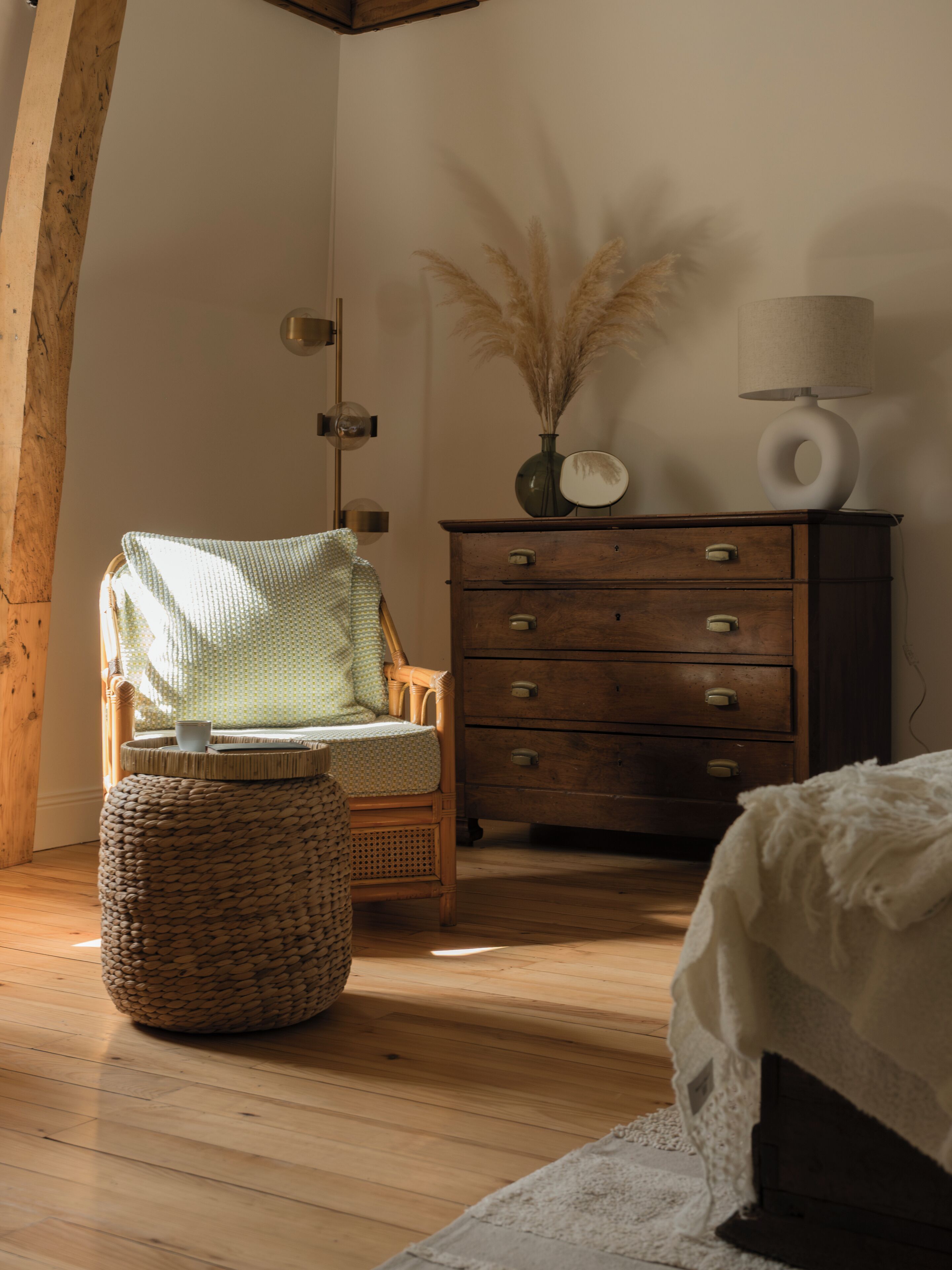 A cozy room with a wicker chair, a wooden dresser, and a bed.