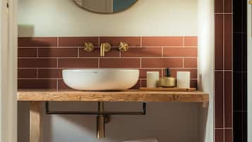Une salle de bain avec un meuble-lavabo en bois, un lavabo blanc et un miroir au-dessus.
