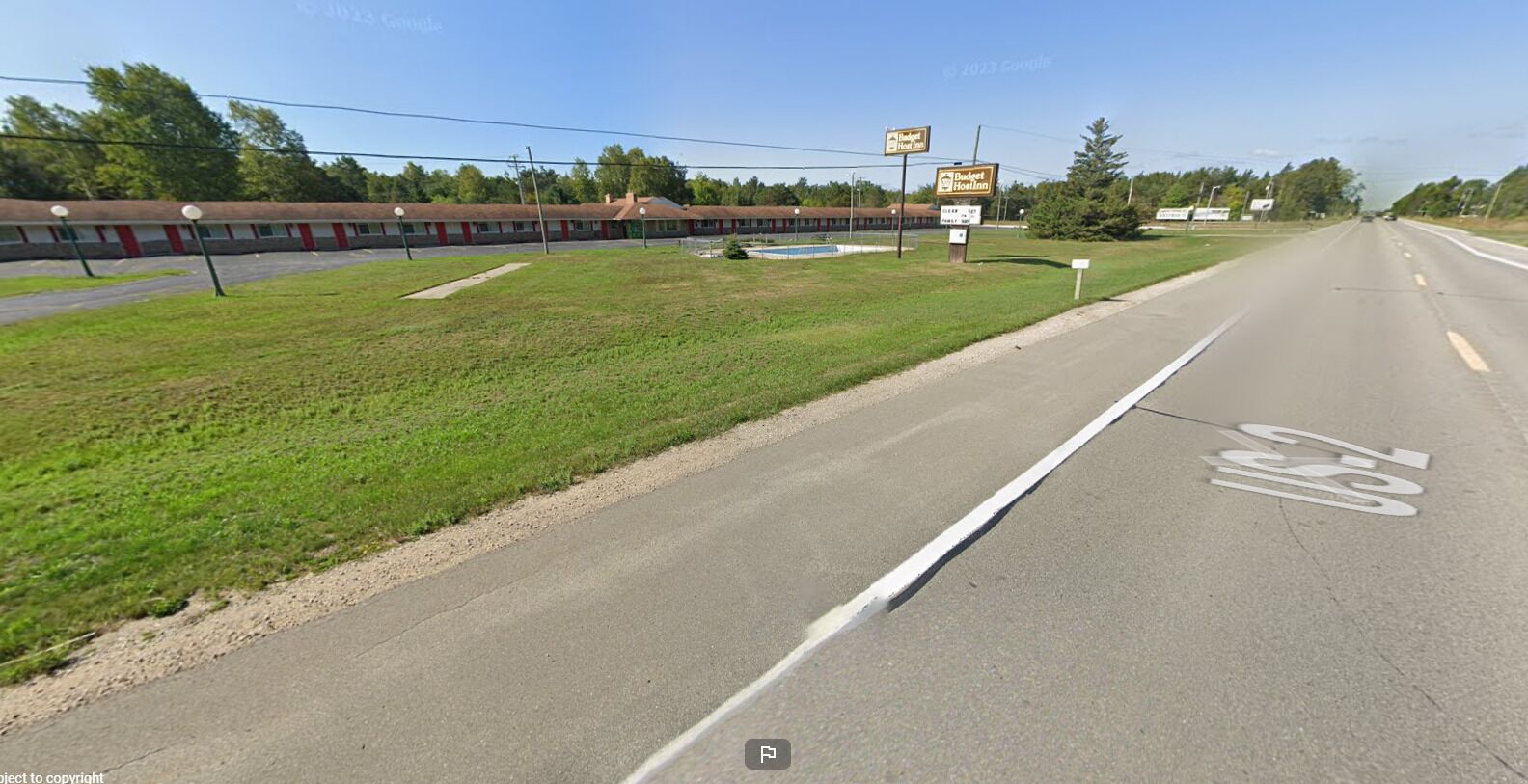 A motel with a row of rooms, a swimming pool, and a sign for Budget Inn.