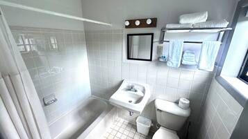 A bathroom with a bathtub, toilet, sink, and a mirror.