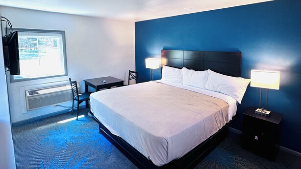 Habitación de hotel con cama, lámparas de noche, escritorio y una silla.